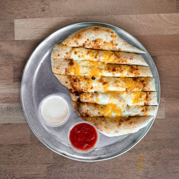 Cheesy toasted flatbread slices arranged on a metal plate with creamy dipping sauce and red salsa.